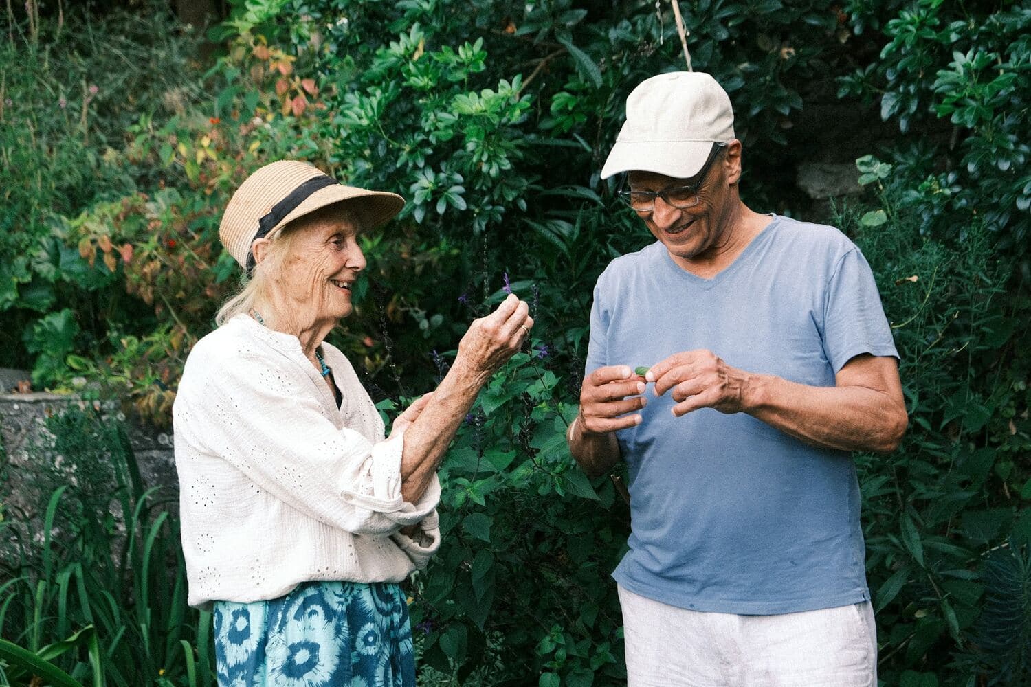 Una pareja de adultos mayores revisa unas hojas en su jardín