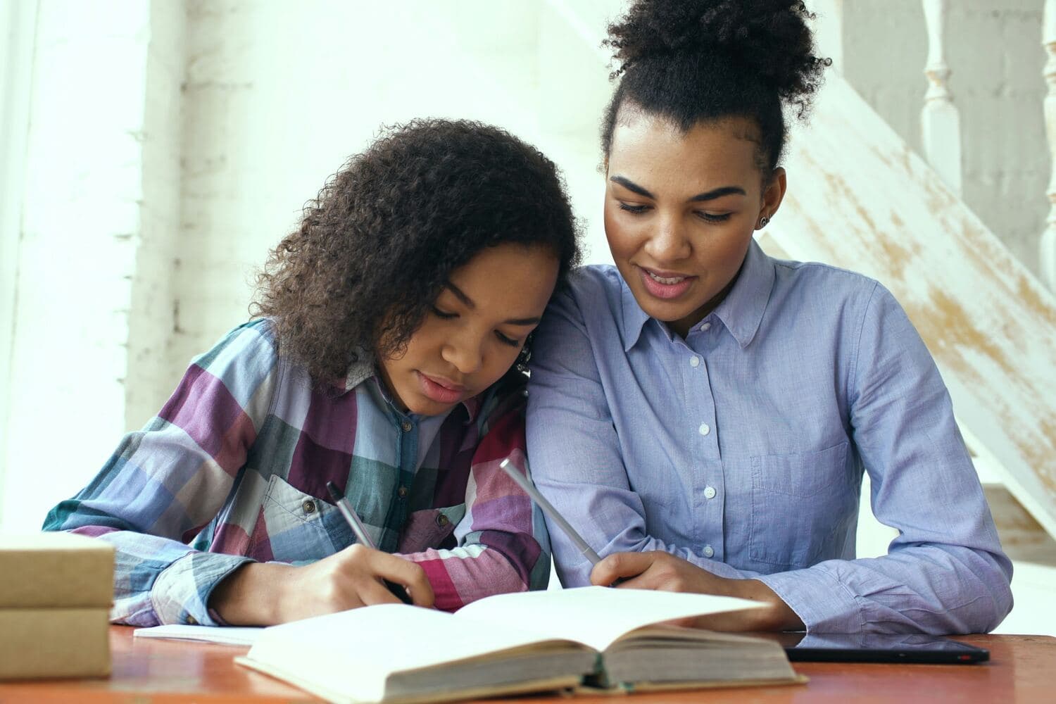 Madre e hija leen juntas un libro en la mesa de estudio