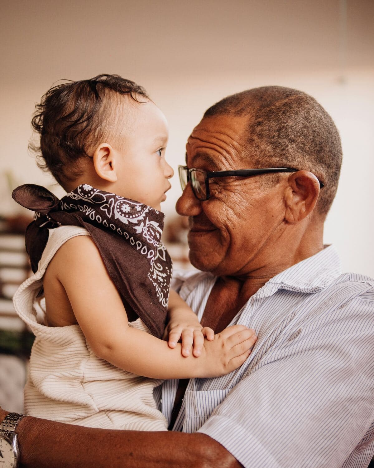 Un abuelo carga a su nieto pequeño y se miran frente a frente